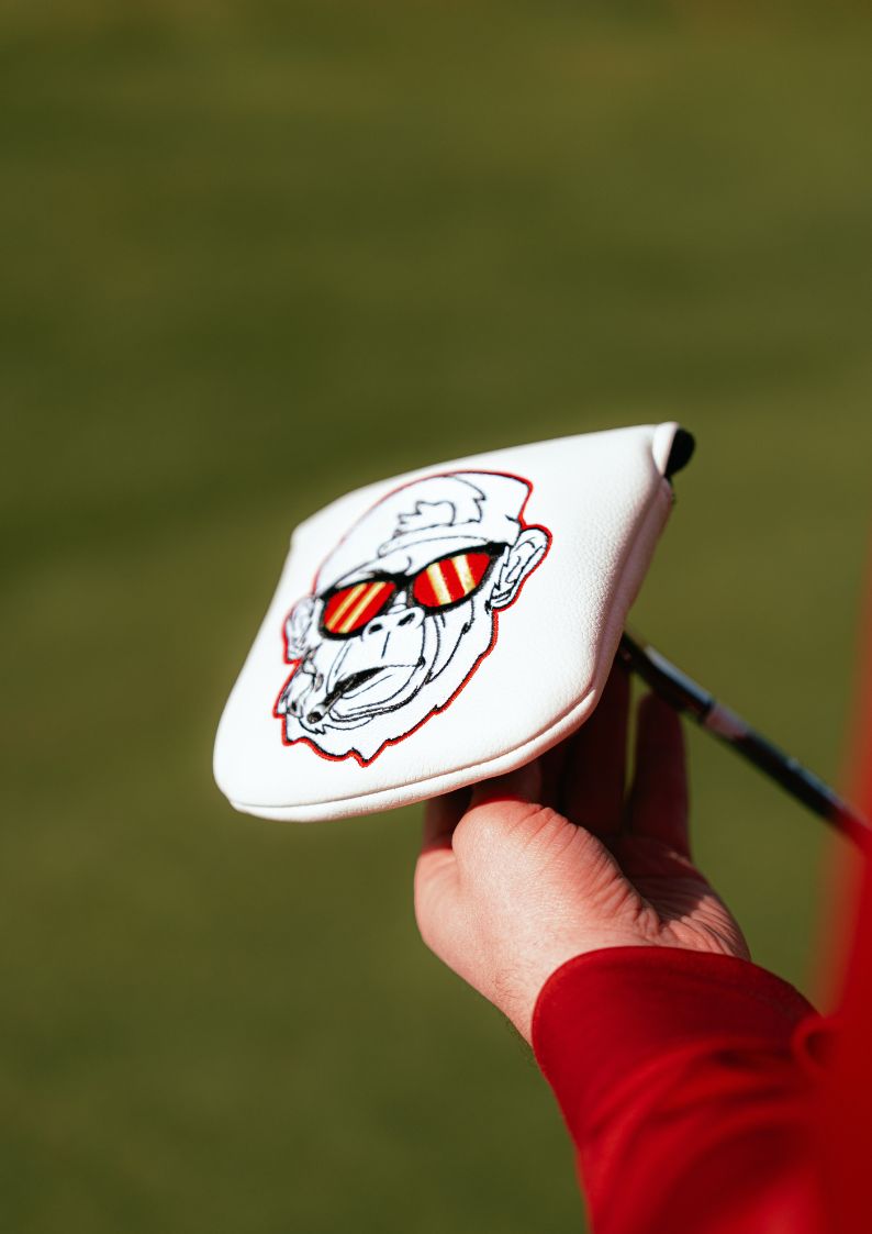 Golf club head cover with a gorilla design on a blurred green background