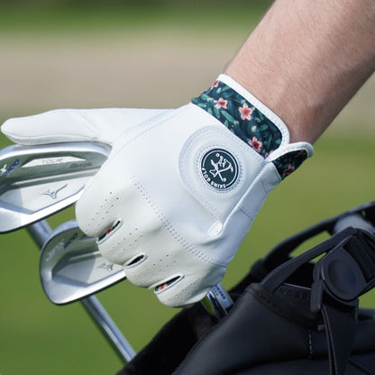White golf glove with floral wristband on a blurred golf course background