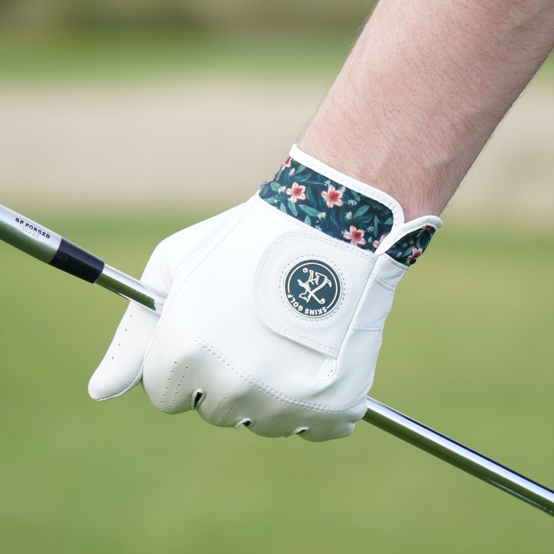 White golf glove with floral wristband on a blurred green background