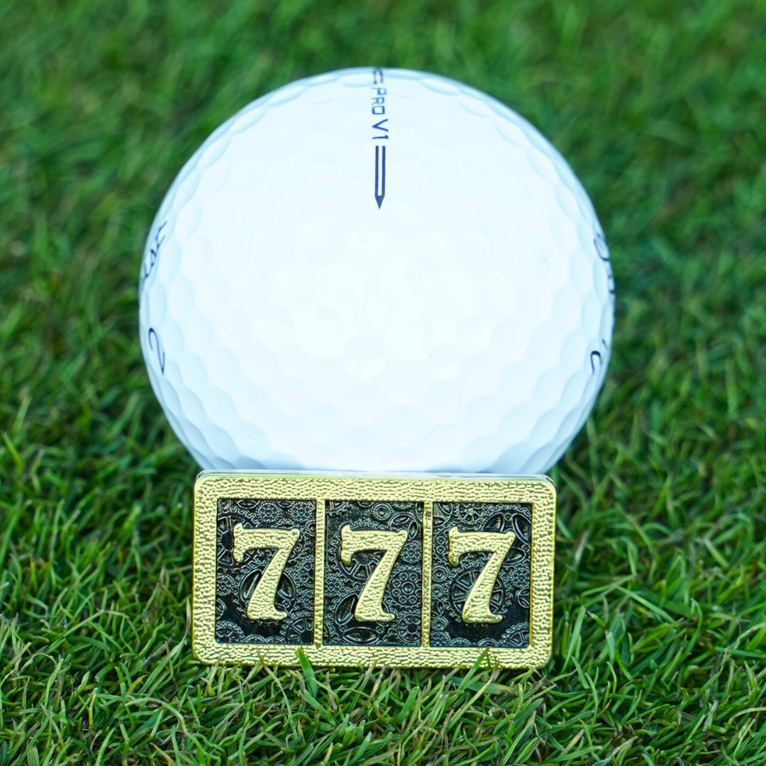 White golf ball on grass with a gold number '7' marker