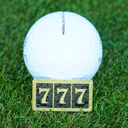 White golf ball on grass with a gold number '7' marker