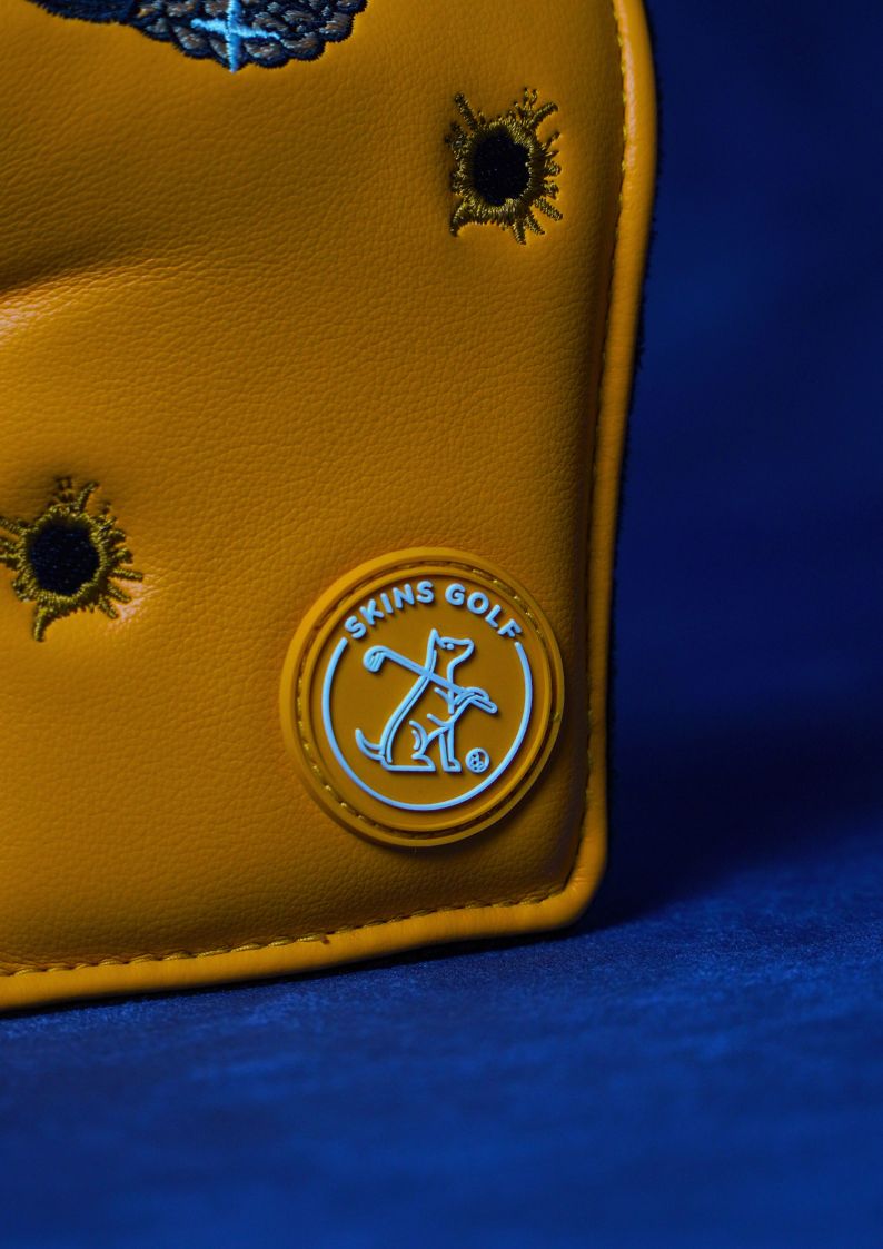 Orange golf headcover with 'Skins Golf' logo on a blue background