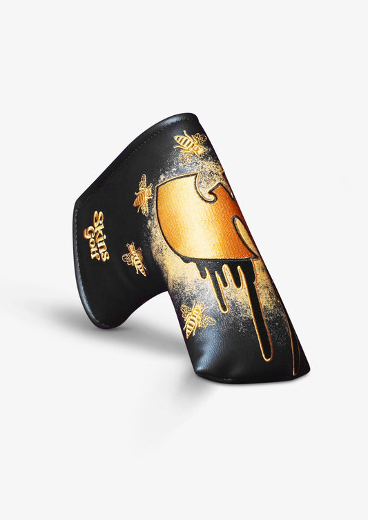 A black putter headcover featuring a gold dripping paint design and gold bee illustrations, displayed on a clean white background.