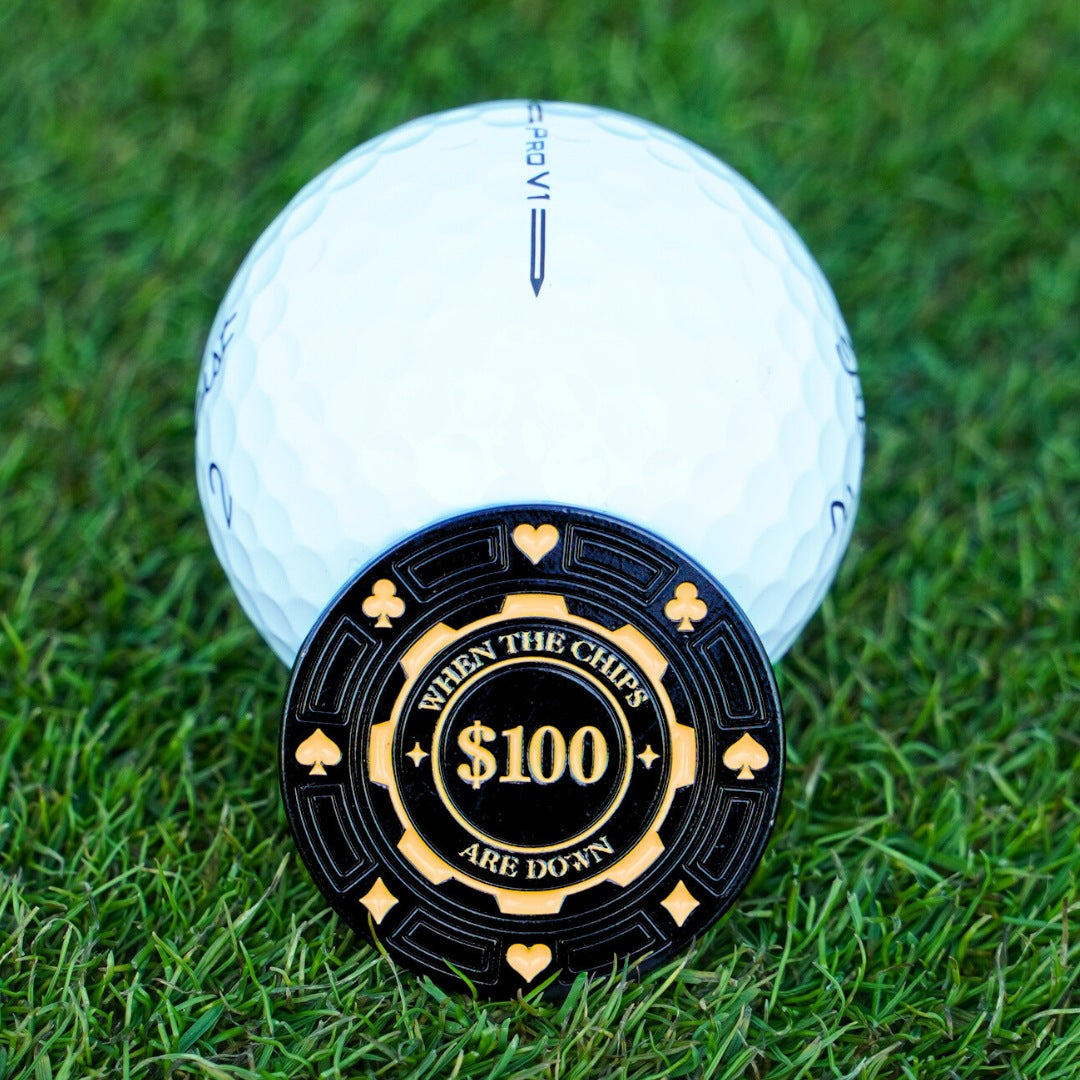 Golf ball with a $100 poker chip on grass