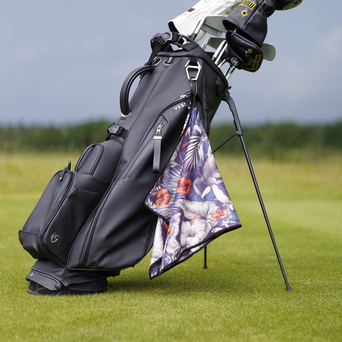 Golf bag with floral towel and golf club on a grassy field